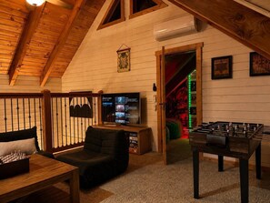Habitació acollidora amb televisió, taula de futbolí, sofà i taula d'escacs.