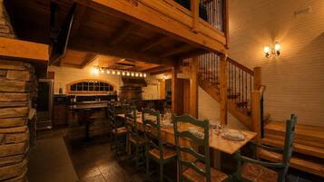 Un espace repas doté d’un plafond haut, de poutres en bois et d’un escalier menant à un niveau supérieur.