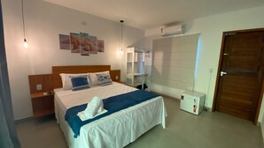 Ein Hotelzimmer mit einem Bett, Nachttischen, einem Kleiderschrank, einer Klimaanlage und einer Tür.