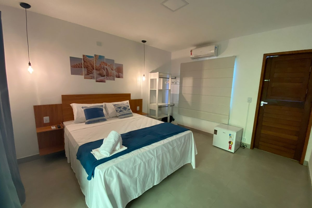 Ein Hotelzimmer mit einem Bett, Nachttischen, einem Kleiderschrank, einer Klimaanlage und einer Tür.