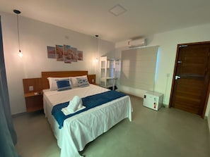 A hotel room with a bed, bedside tables, a wardrobe, an air conditioning unit, and a door. - Villa Suites Gostoso (São Miguel do Gostoso)