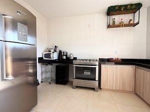 Una cocina con refrigerador de acero inoxidable, microondas, cafetera y horno.