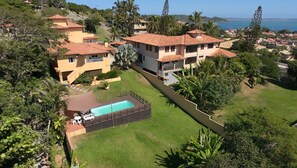 Un barrio residencial con casas, una piscina y vistas al mar.