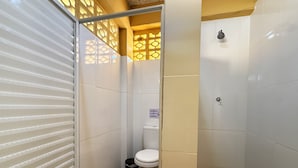 Een compacte, afgesloten badkamer met toilet, een prullenbak en een douche.