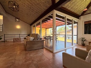 An open-plan living area with a sliding glass door leading to an outdoor patio. - Villa em João Fernandes com Piscina (Buzios)