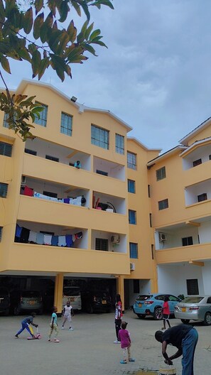 A multi-story building with balconies, a parking area, and a clear sky. - Comfortable and safe place not to far from the beach and it is family friendly. (Mombasa)