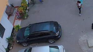 En gatubild med två parkerade bilar och fotgängare.