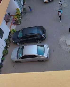 A street view with two parked cars and pedestrians. - Comfortable and safe place not to far from the beach and it is family friendly. (Mombasa)