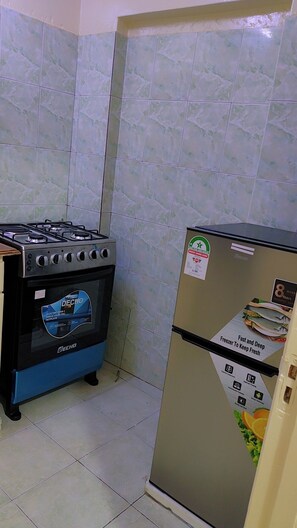 A kitchen with a gas stove, an electric oven, and a refrigerator. - Comfortable and safe place not to far from the beach and it is family friendly. (Mombasa)