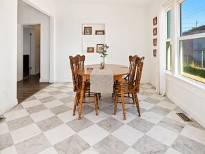 Ein Essbereich mit Schachbrettboden, Holzkästen, einem runden Tisch und gerahmten Bildern an der Wand.