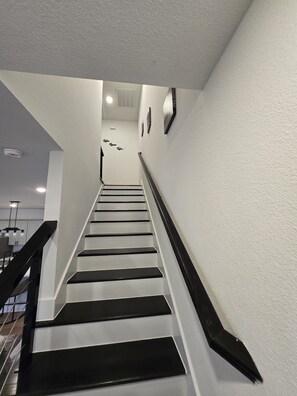 A staircase with a handrail, leading to an upper floor. - Football Season in Houston | NRG Stadium | 2BR (Houston)