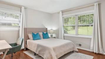 A hotel room with a bed, a desk, a chair, and a window with curtains.