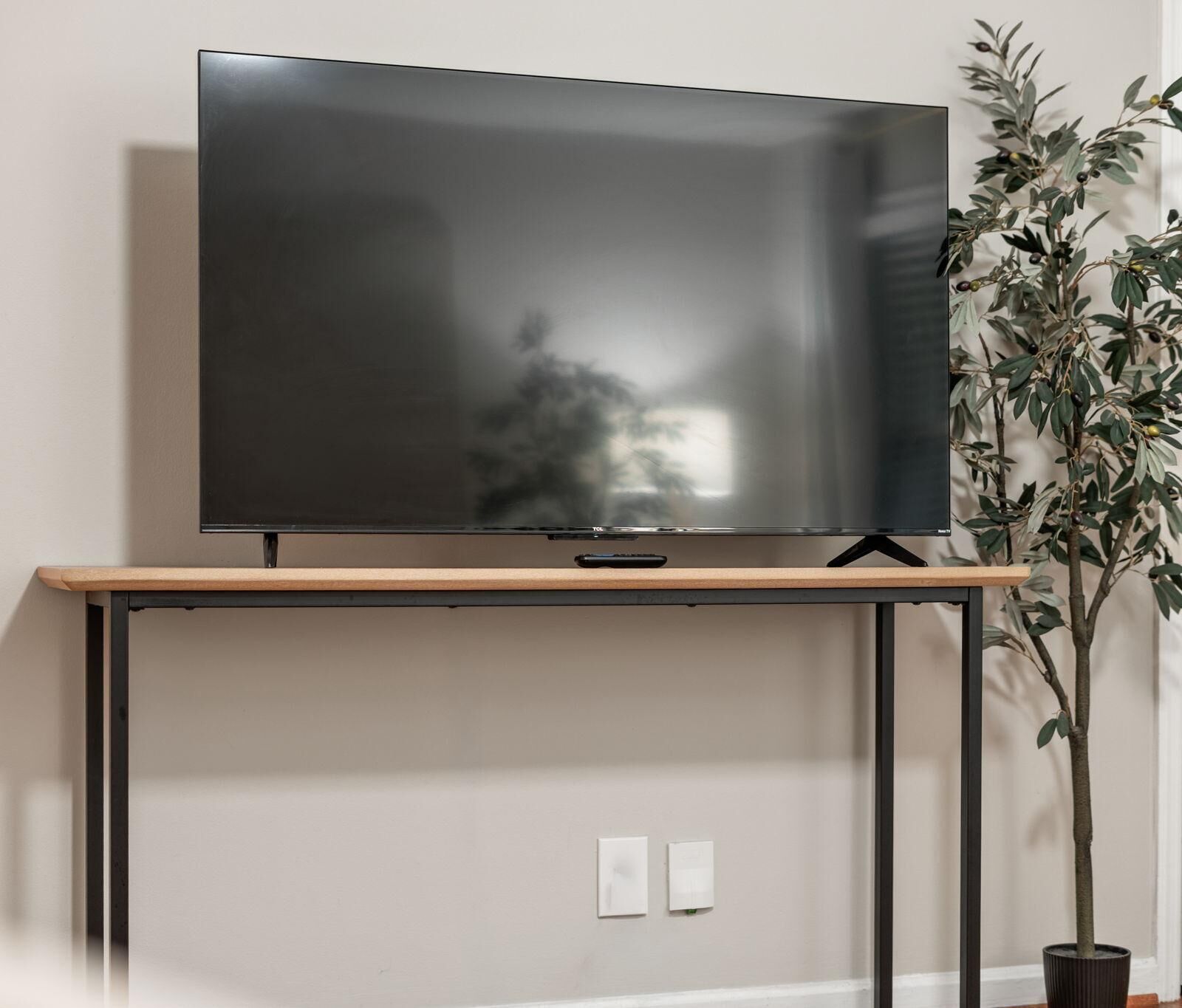 Een flatscreen televisie bevestigd aan een houten tv-meubel met metalen frame.