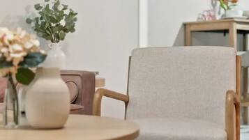 A room with a round wooden table, a beige armchair, and a patterned rug.