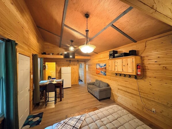 L’intérieur d’un chalet confortable, avec un coin repas, un canapé et un lit.