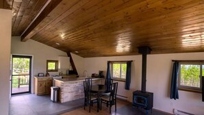 A spacious kitchen with a central island, a dining area with chairs, a built-in stove, and large windows providing natural light.