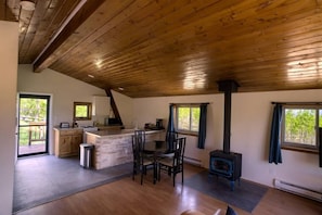 A spacious kitchen with a central island, a dining area with chairs, a built-in stove, and large windows providing natural light.
