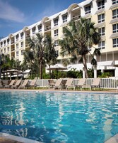 Un hotel con piscina, palmeras y sillones de descanso.