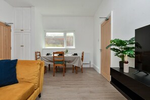 A room with a dining table set for four, a sofa, a television, and a potted plant. - Contractor-Friendly 6BR 6 En-Suites | Free Parking (Kent)