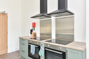 A modern kitchen with a stainless steel range hood, a built-in oven, and a countertop with a knife block. - Contractor-Friendly 6BR 6 En-Suites | Free Parking (Kent)