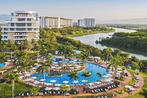 A resort with a large central pool, palm trees, and a river in the background. - Spacious Luxury 4-BR Luxxe Residence in Nuevo Vallarta by Vidanta (Las Jarretaderas)