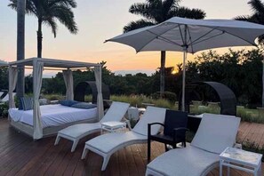 Eine Terrasse mit Baldachin, Liegestühlen und einem Bett ebenfalls unter einem Baldachin.