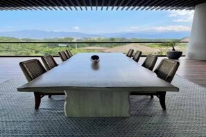 A conference table with chairs, a potted plant, and a view of the landscape. - Spacious Luxury 4-BR Luxxe Residence in Nuevo Vallarta by Vidanta (Las Jarretaderas)