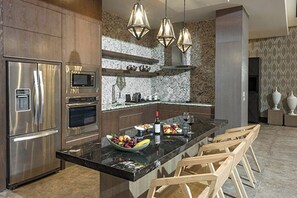 Eine moderne Küche mit Edelstahlgeräten, einer Marmorarbeitsplatte und Holzbarhocker.