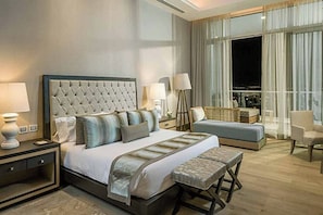 A modern hotel room with a large bed, bedside lamps, a bench, and a view of the city at night. - Spacious Luxury 4-BR Luxxe Residence in Nuevo Vallarta by Vidanta (Las Jarretaderas)