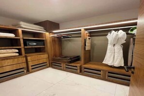 Ein begehbarer Kleiderschrank mit Holzböden, einer Sitzbank und hängender Kleidung.