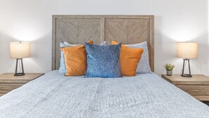 Ein Bett mit einem gemusterten Überwurf, zwei Nachttische mit Lampen und ein Holz-Kopfteil.