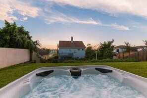 A hot tub in a backyard with a house in the background. - 2 Min. Walk to Beach/Ocean Views/Hot Tub/Game Room/Bikes/In-Law Suite (St. Augustine)