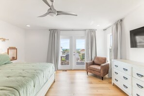 Une chambre à coucher avec un lit, une chaise, une commode et un ventilateur de plafond.