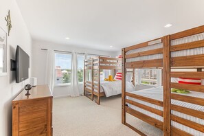 A bedroom with bunk beds, a television, a dresser, and a window with curtains. - 2 Min. Walk to Beach/Ocean Views/Hot Tub/Game Room/Bikes/In-Law Suite (St. Augustine)