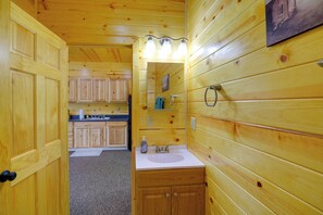 L’intérieur d’une cabane en bois comprend une salle de bain équipée d’un lavabo, d’un miroir et d’un meuble-lavabo.