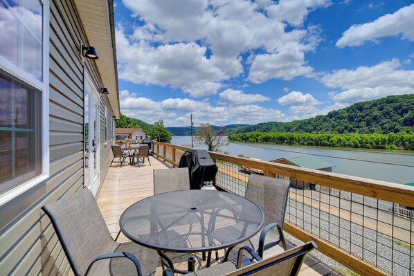 Une terrasse dotée de mobilier d’extérieur, d’un barbecue et offrant une vue sur une rivière et une forêt.