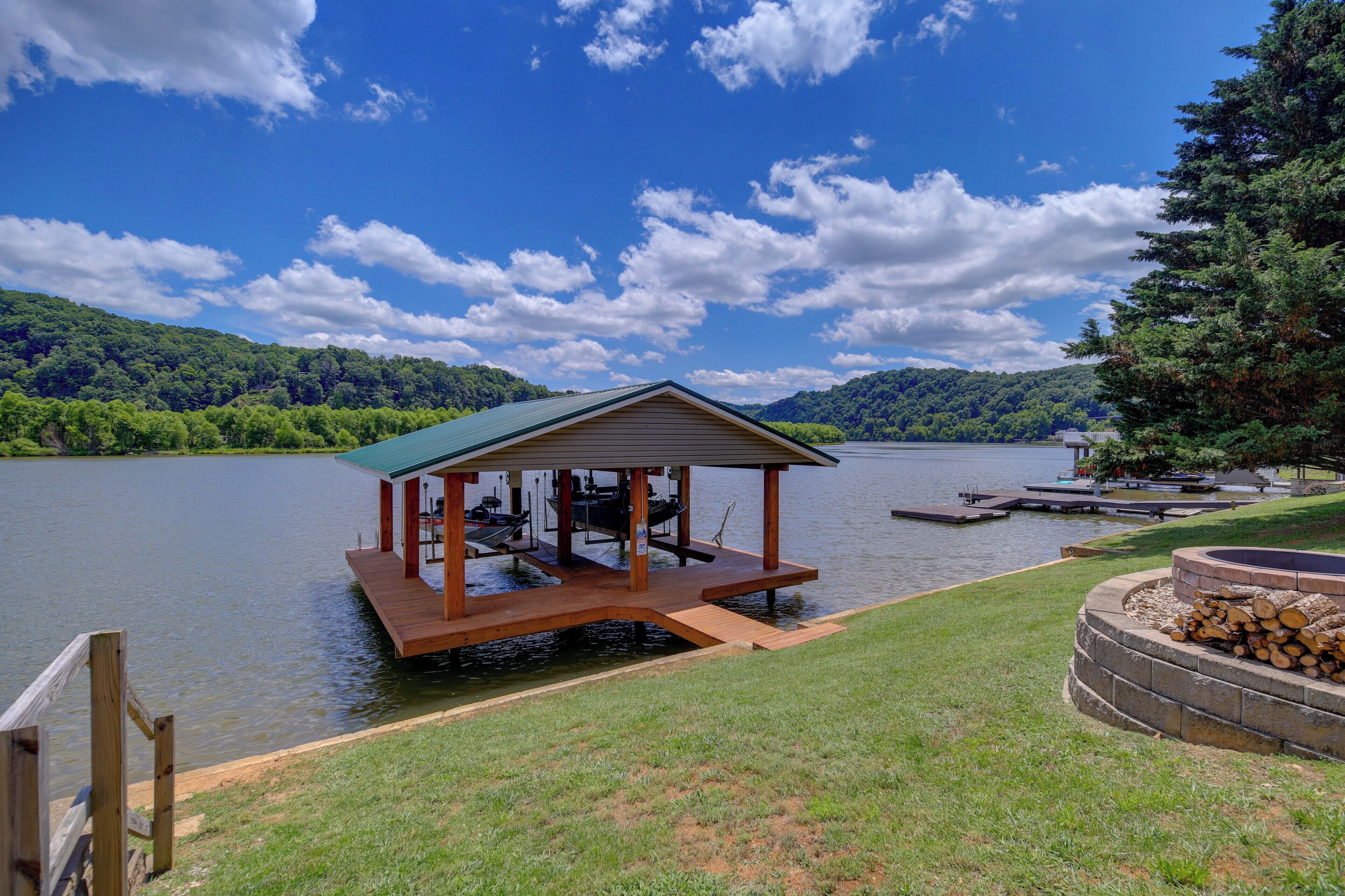 Une terrasse en bois surmontée d’un toit végétalisé, située au bord d’un lac et entourée d’herbe et d’arbres.