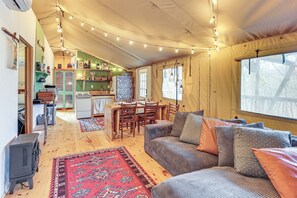 A cozy living room with a sofa, a rug, and a dining area with chairs and a table.