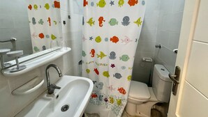 A bathroom with a shower curtain featuring colorful fish and sea creatures, a sink with a faucet, and a toilet. - Modern Pool-View Studio with Gym, Pool Pub & Restaurant in Aqua Palms Resort (Hurghada)