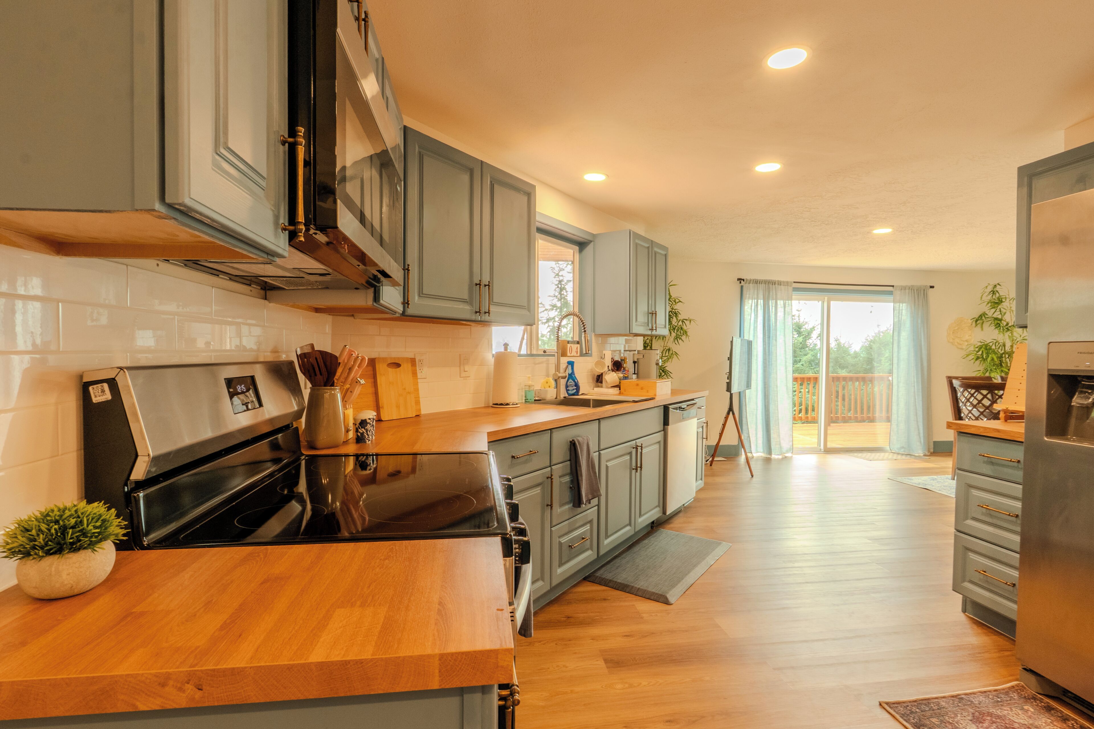 A modern kitchen with grey cabinets, a black stove, and wooden countertops.