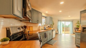 A modern kitchen with grey cabinets, a black stove, and wooden countertops. - 3 Bedroom Art Retreat with Billiards and Art Studio near Portland (Vancouver)
