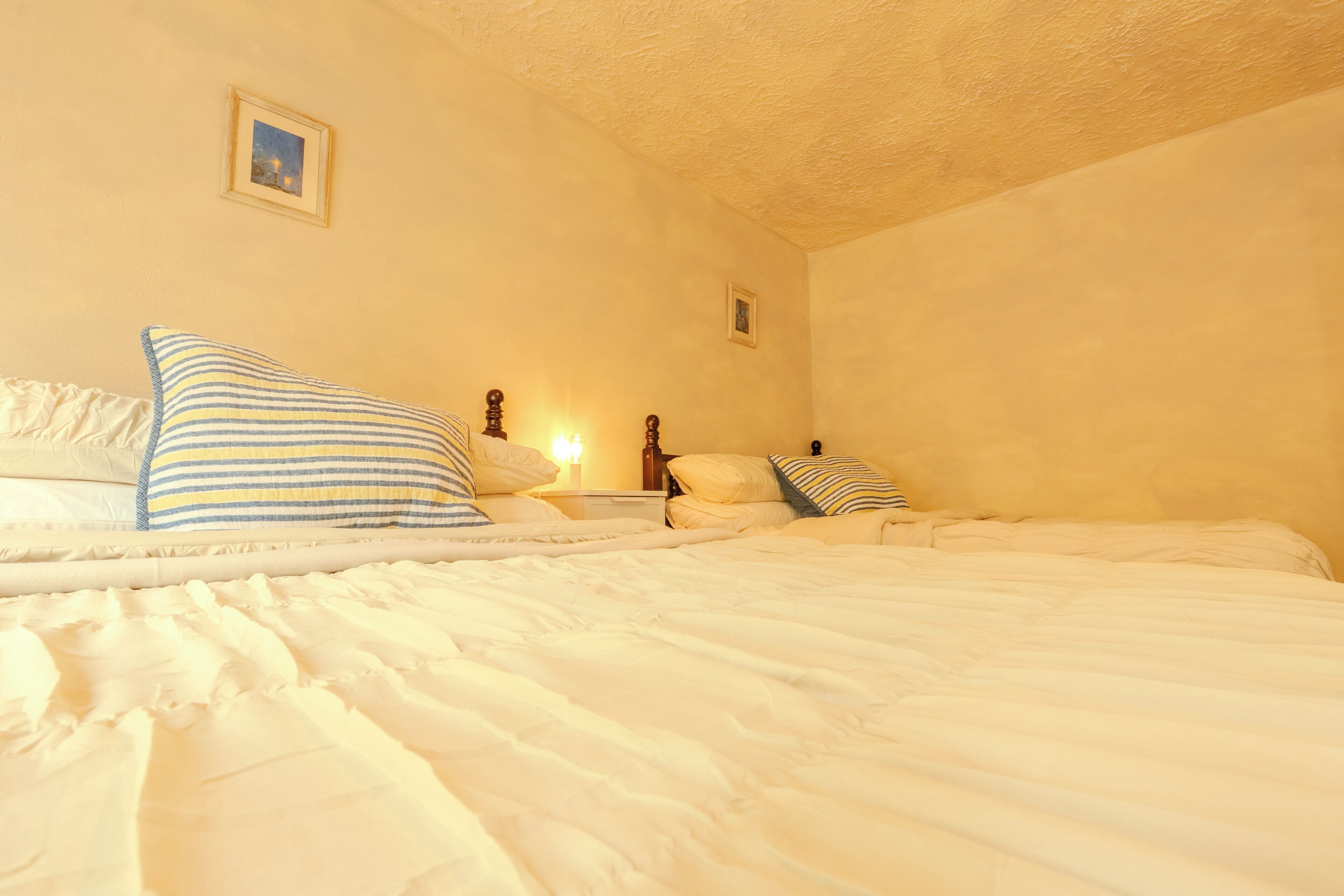 Une chambre à coucher avec un lit, des oreillers, une table de chevet et un tableau accroché au mur.