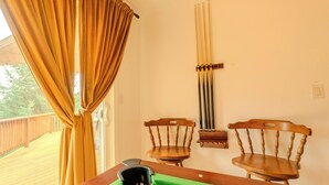 A pool table with cue sticks, two wooden chairs, and a window with curtains. - 3 Bedroom Art Retreat with Billiards and Art Studio near Portland (Vancouver)
