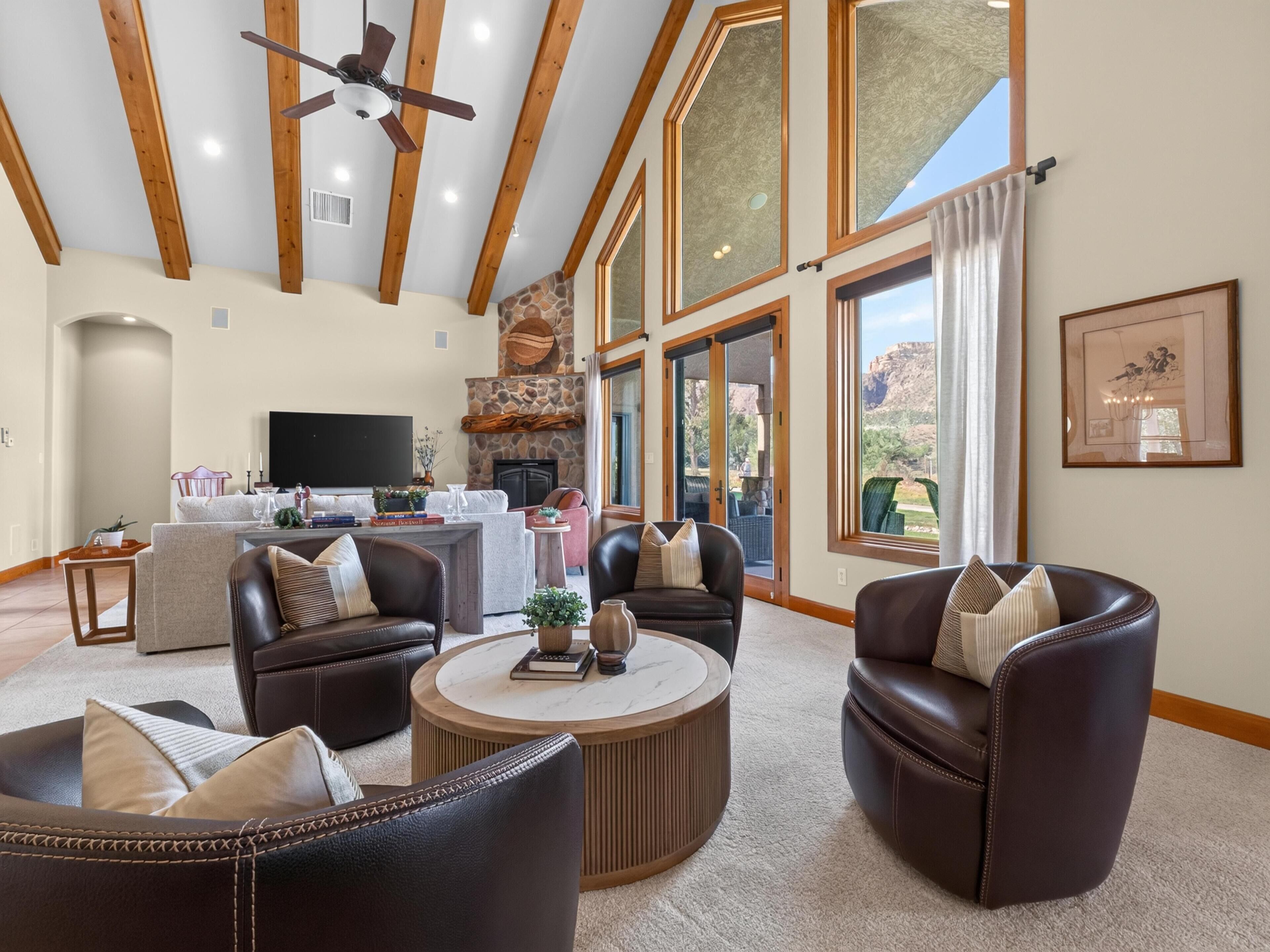 A spacious living room with leather sofas, a coffee table, and a fireplace.