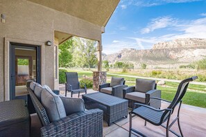Eine Terrasse im Freien mit Korbmöbeln und Blick auf eine gebirgige Landschaft.