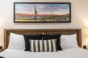 A bed with white bedding and two pillows, one striped and one solid black, against a wooden headboard. - Fairway Oasis:  Arrowhead Ranch Fairway Retreat with Private Pool (Glendale)