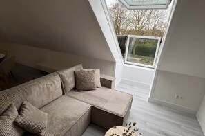 A modern loft bedroom with a sloped ceiling, a built-in sofa, and a skylight.