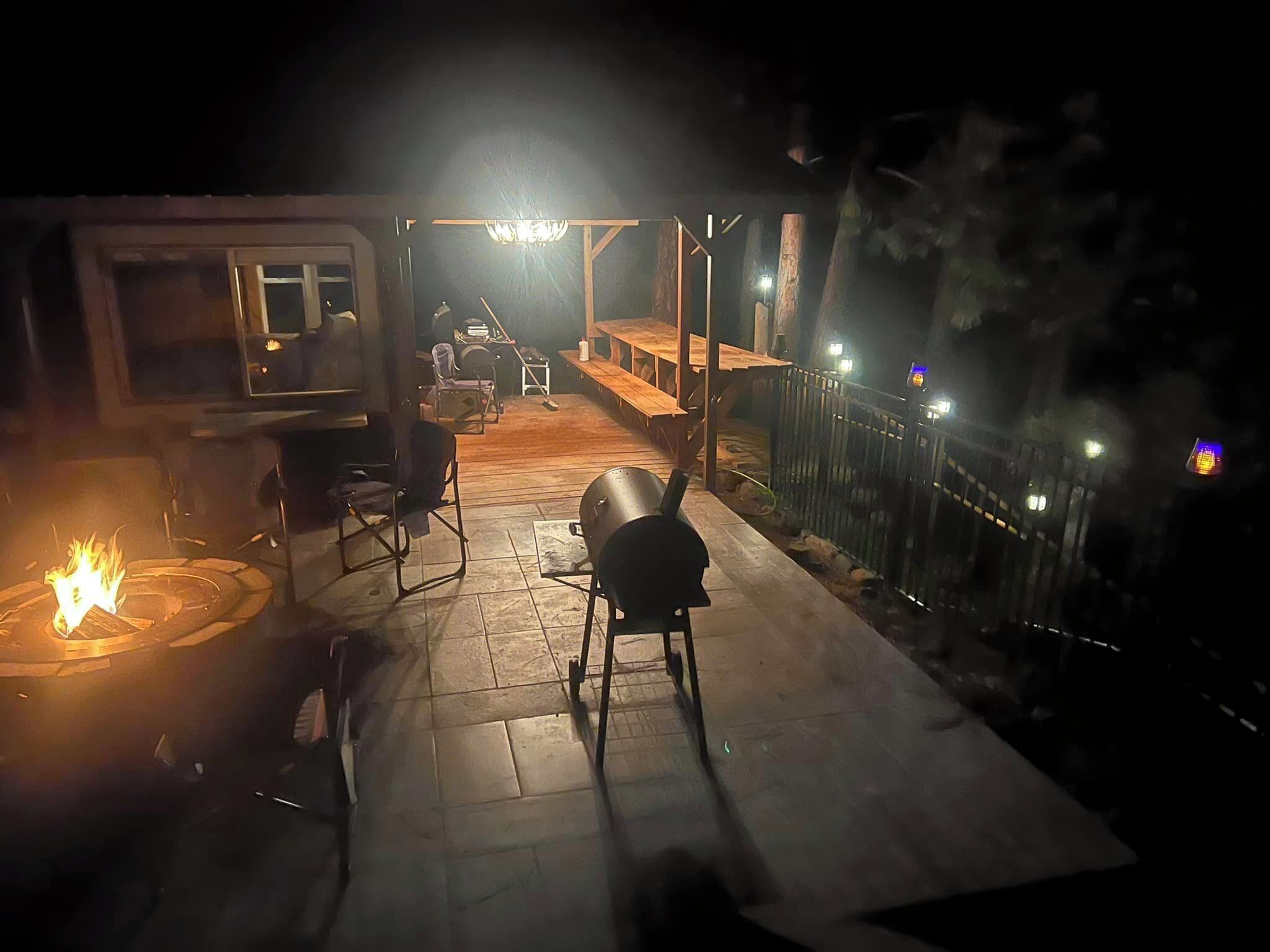 A patio area with a fire pit, outdoor seating, and a covered section with tables and chairs.