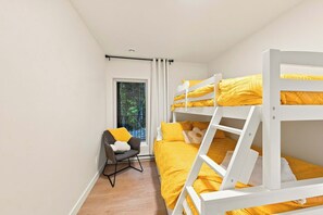 A bunk bed room with a window, a chair, and a view of trees outside.