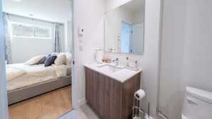 Ein modernes Badezimmer mit einem großen Spiegel, einem Waschbecken und einer Toilette.